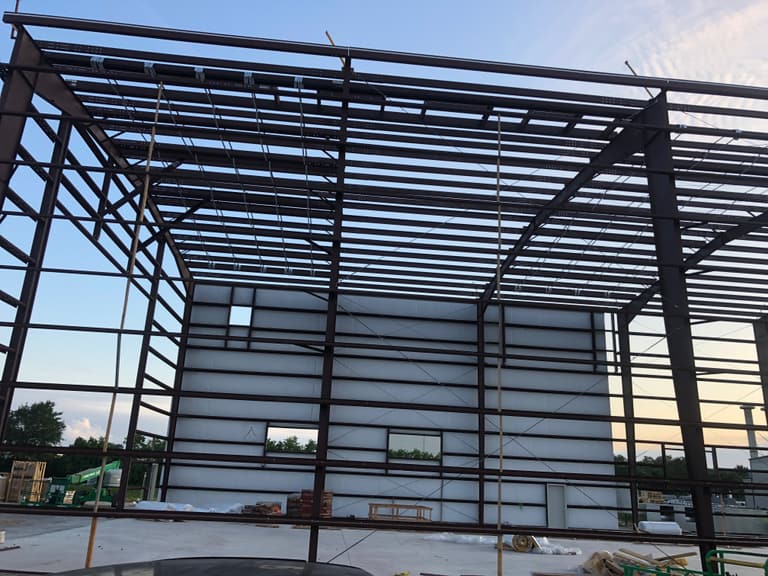 Steel frame with roof purlins and girts in place and an insulated endwall with framed door and window openings